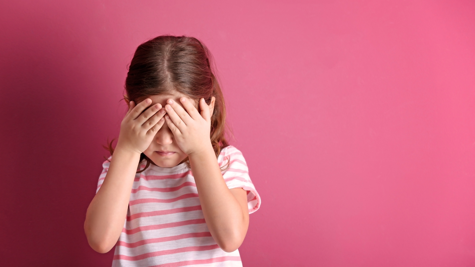 Child covering her face to show shyness or lack of confidence